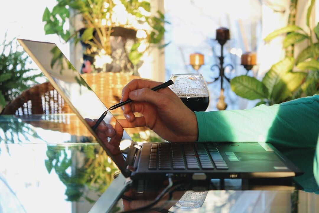 Journalist hands writing notes at a desk with a laptop